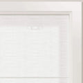 Photograph of a white textured window blind inside a clean white frame showing subtle light filtering