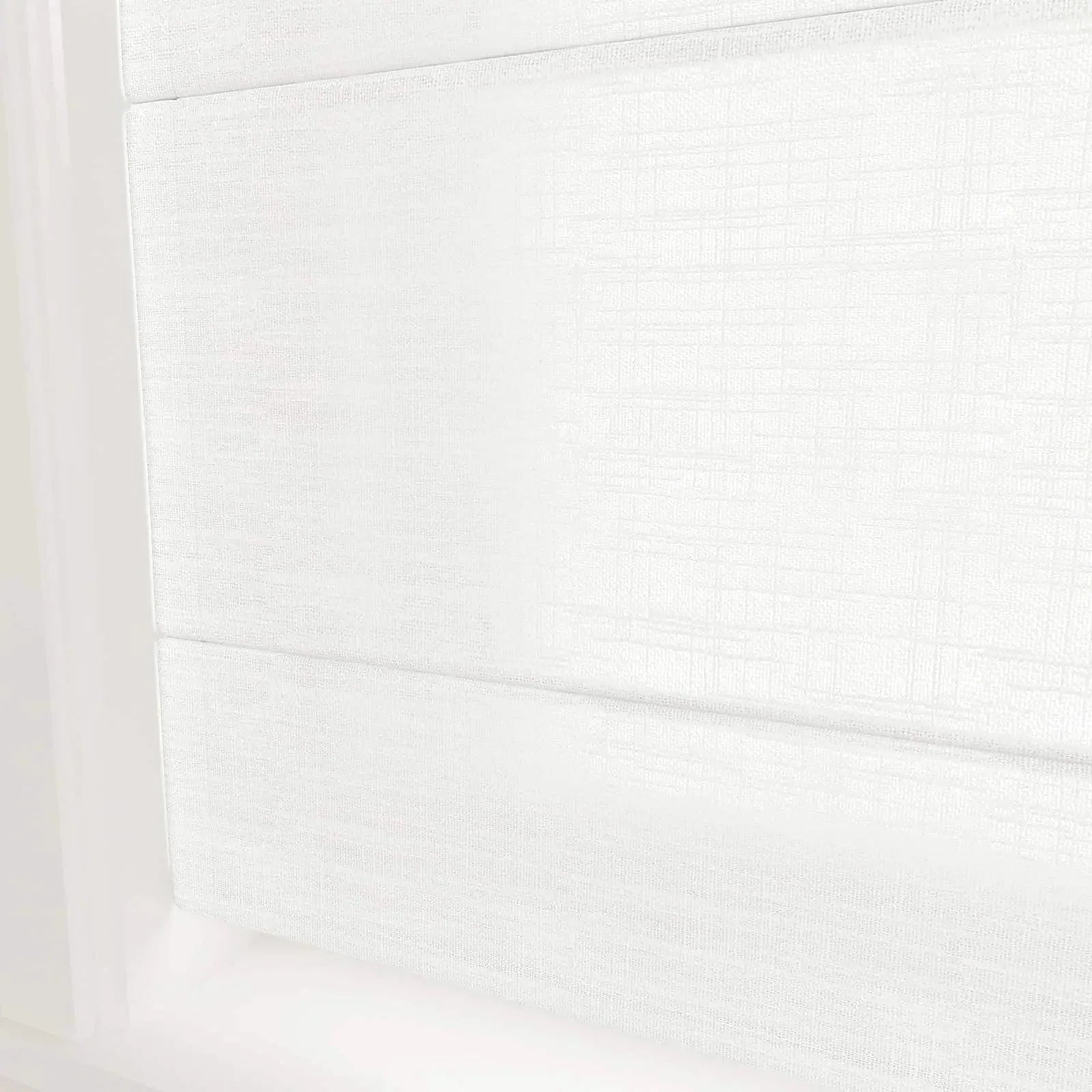 A pure white fabric Roman window blind with a subtle woven texture and gentle horizontal folds filtering light in a modern interior