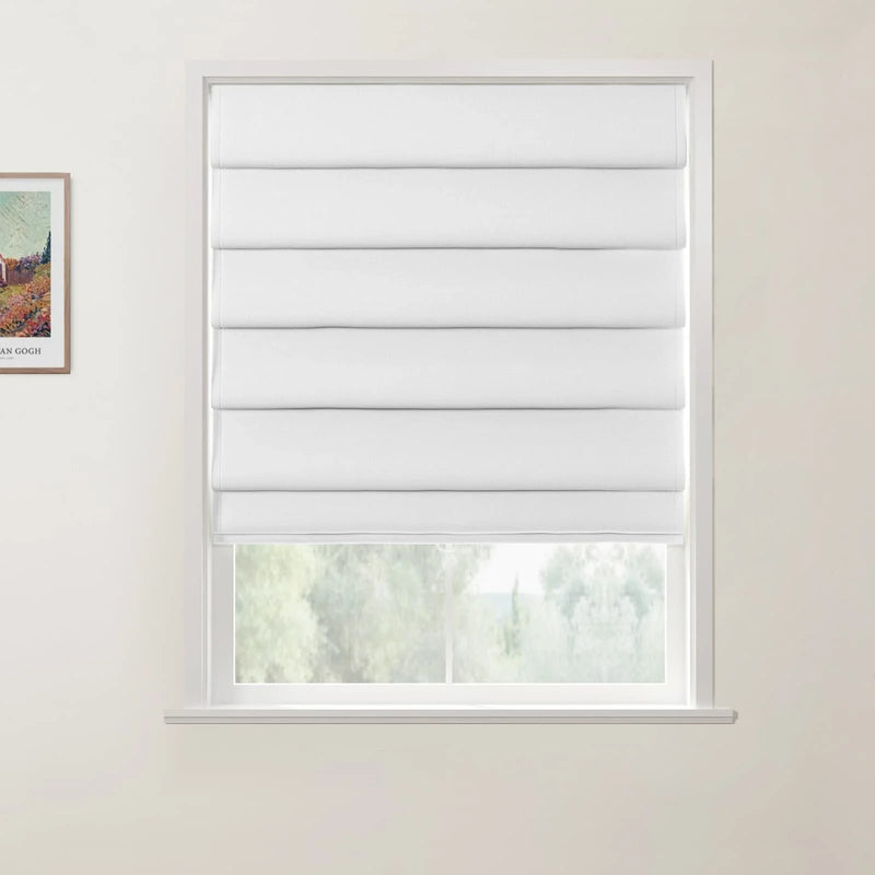 Framed print by Vincent van Gogh depicting a vibrant rural landscape with a red-roofed building and colorful fields hangs on a light beige wall beside a window fitted with a white layered fabric Roman blind that partially reveals a blurry green outdoor landscape