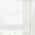 A translucent white Roman blind with clean horizontal folds and visible lift cords featuring small clips, gently filtering natural light from an outdoor green landscape