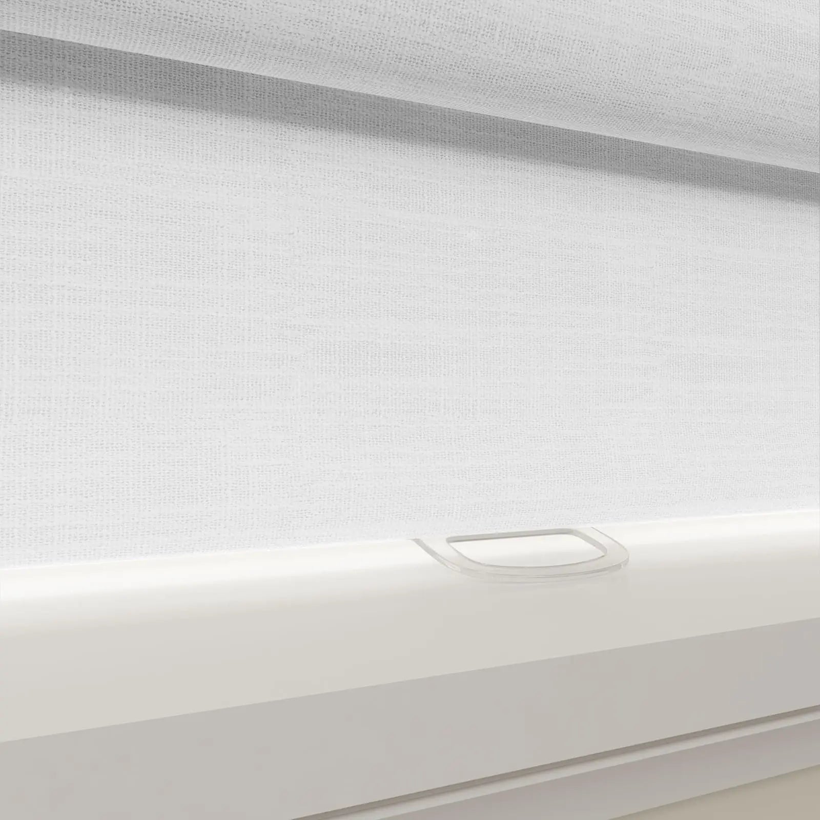 A modern white textured fabric roller blind on a window, featuring a sleek white bottom rail and a clear plastic pull tab