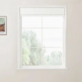 Framed print by Van Gogh on a light beige interior wall alongside a multi-pane white window featuring a partially raised white Roman shade and a blurred green outdoor view
