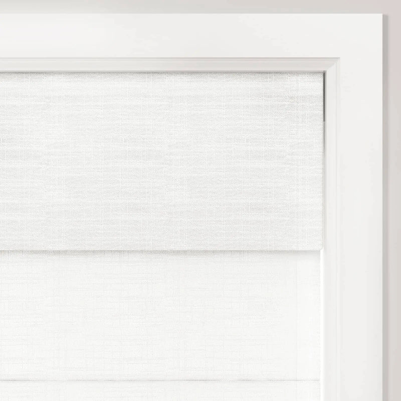 A close-up of a double-layered white textured fabric window shade installed within a bright white wooden window frame providing a minimalist aesthetic