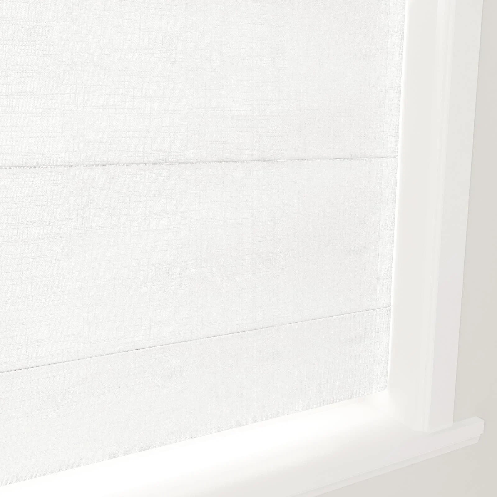 White fabric Roman shades with subtle texture and clean horizontal folds, installed in a bright white window frame and sill