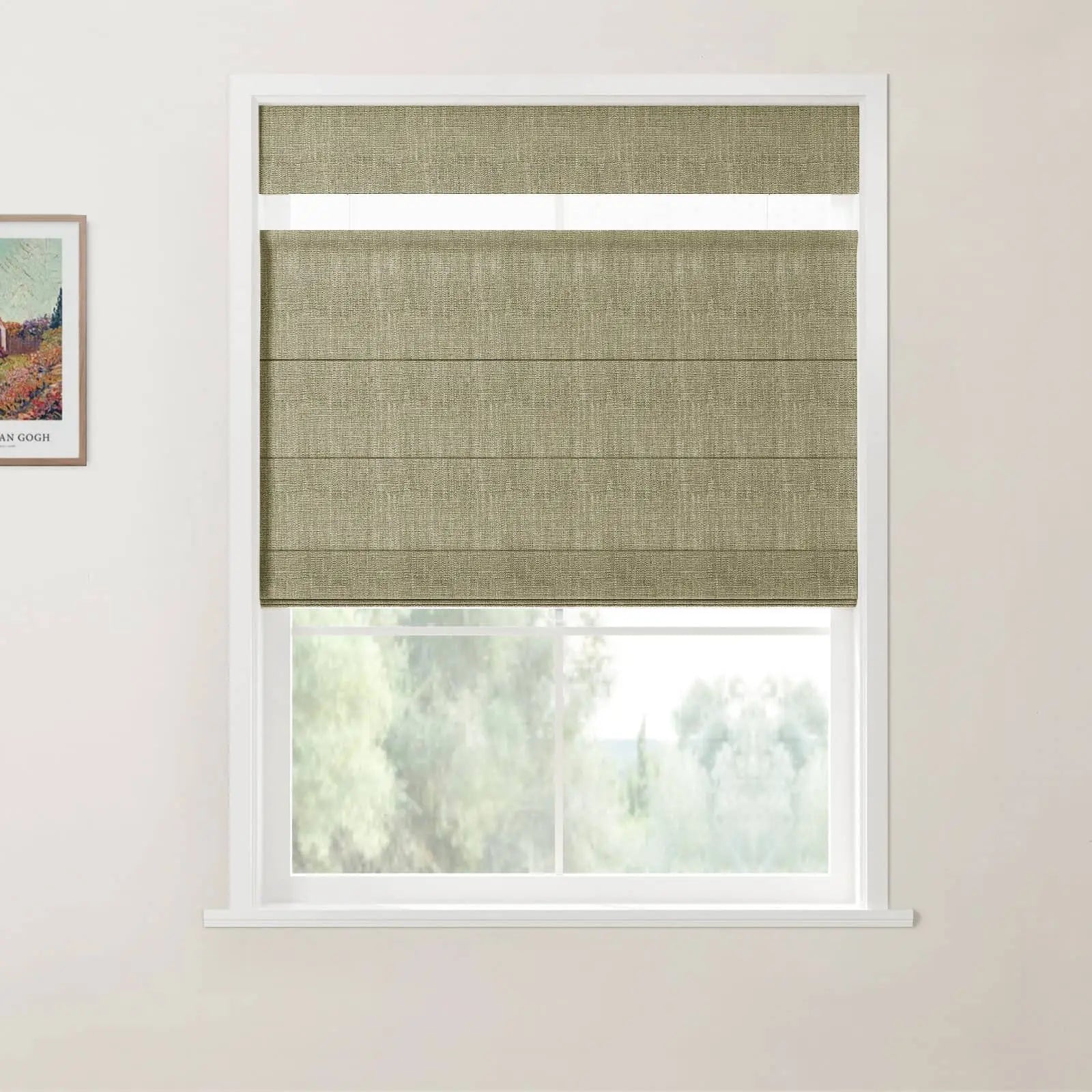 Photograph featuring a window in an indoor room with an olive green textured top-down bottom-up Roman blind, a white frame, and a visible portion of a framed Van Gogh landscape print on the left, looking out onto a blurred backdrop of green trees