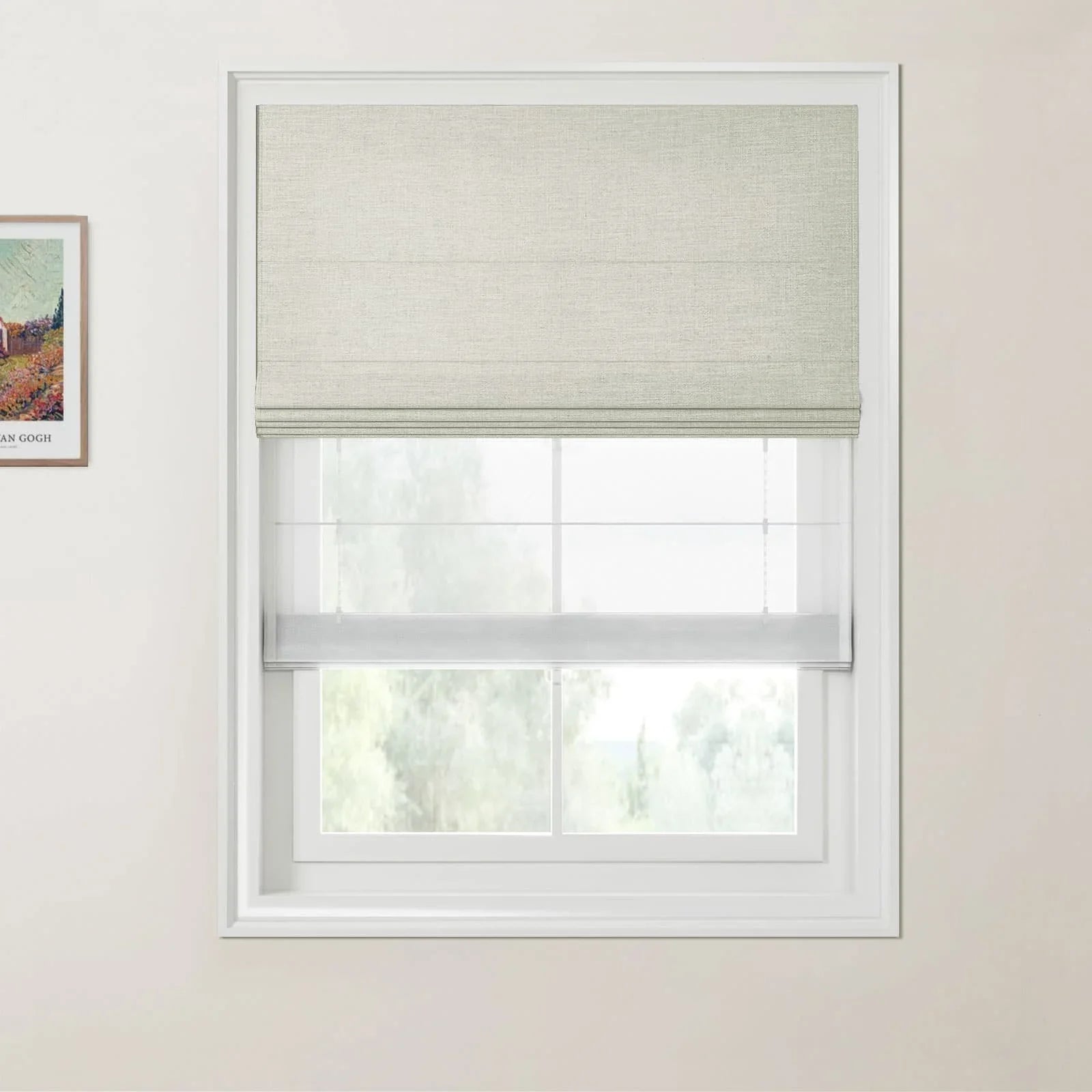 A framed print of a colorful Van Gogh landscape painting on the wall beside a window dressed with a light gray textured Roman blind, a sheer white privacy blind, and a soft green natural view