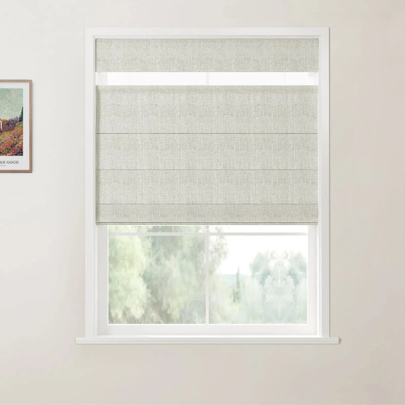 Photograph of a room interior featuring a white-framed window with a light grey textured Roman blind partially lowered over a view of blurred green trees, alongside a framed print of a colorful Van Gogh painting on the adjacent wall