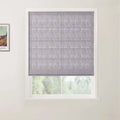 Photograph showing a grey textured Roman blind on a white-framed window, alongside a partial Van Gogh print on the left wall and blurred green trees outside
