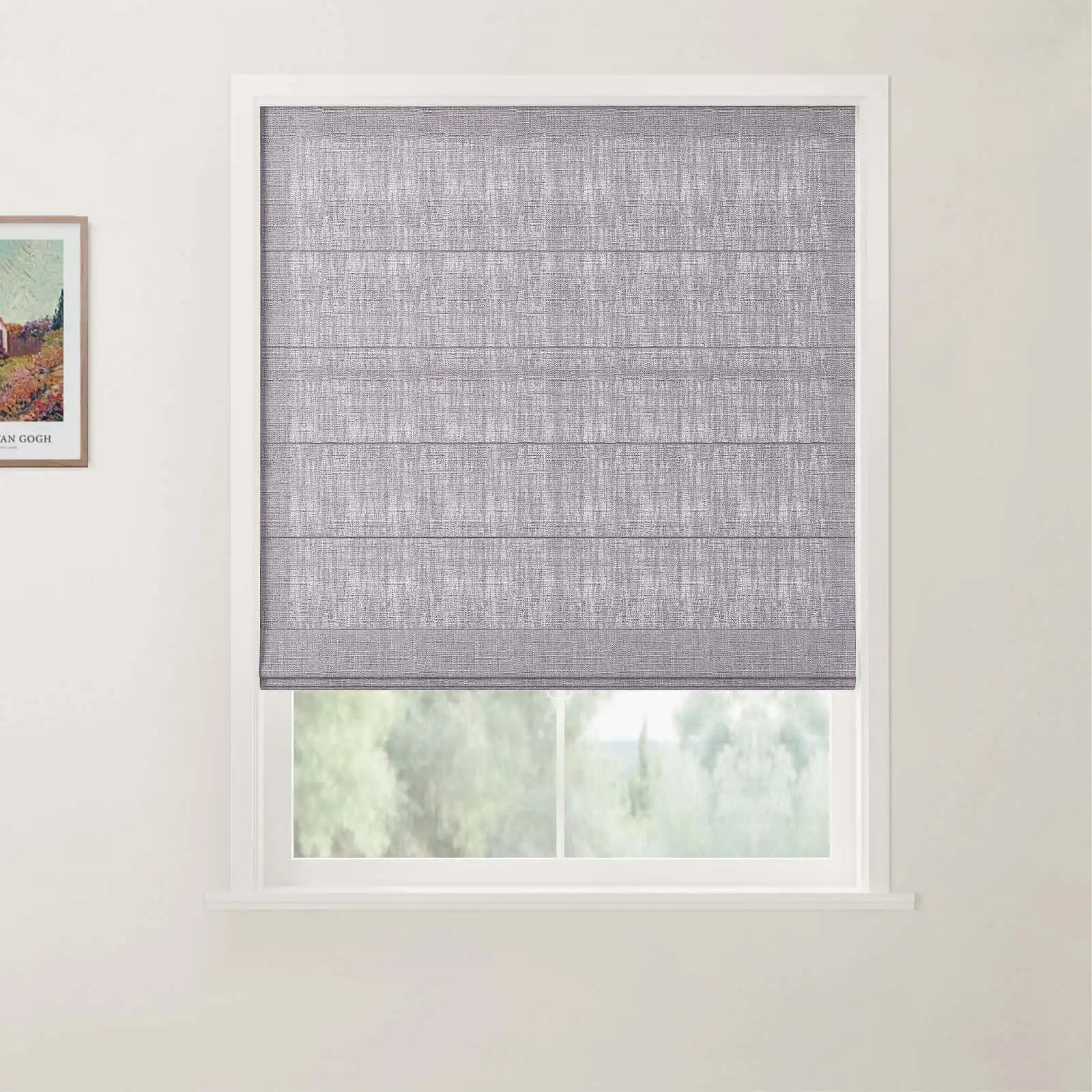 Photograph showing a grey textured Roman blind on a white-framed window, alongside a partial Van Gogh print on the left wall and blurred green trees outside