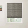 Photograph of a window featuring a dark grey textured Roman blind with horizontal pleats partially open to a blurred green outdoor view, with a framed Van Gogh print depicting a vibrant landscape visible on the left wall