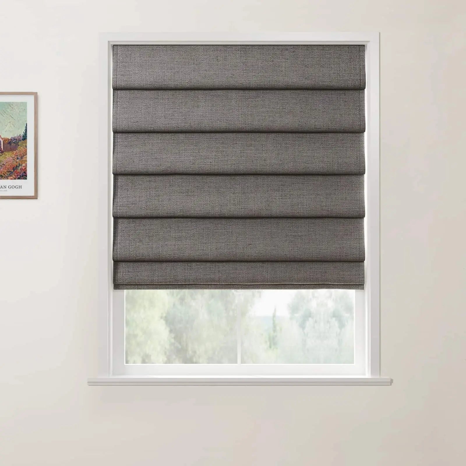 Textile dark gray textured Roman blind covering a window in a light-colored room, partially open to reveal a soft green outdoor landscape, with a framed print of Vincent van Gogh's Wheat Field with Cypresses visible on the adjacent white wall