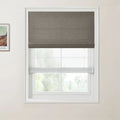 Print by Vincent van Gogh depicting a landscape, a modern interior window featuring a dark grey textured Roman blind pulled halfway down above a sheer white shade, set against a light beige wall