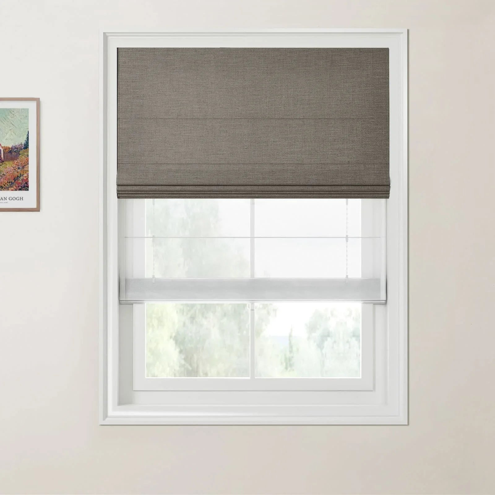 Print by Vincent van Gogh depicting a landscape, a modern interior window featuring a dark grey textured Roman blind pulled halfway down above a sheer white shade, set against a light beige wall
