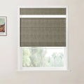 An interior view of a window fitted with a textured greige Roman blind partially raised above a soft green outdoor landscape complemented by a framed Van Gogh print on the left wall