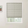 Photograph showing a window with a textured grey-green Roman blind and white frame, beside a framed Van Gogh colorful landscape print featuring a house and trees on a white wall
