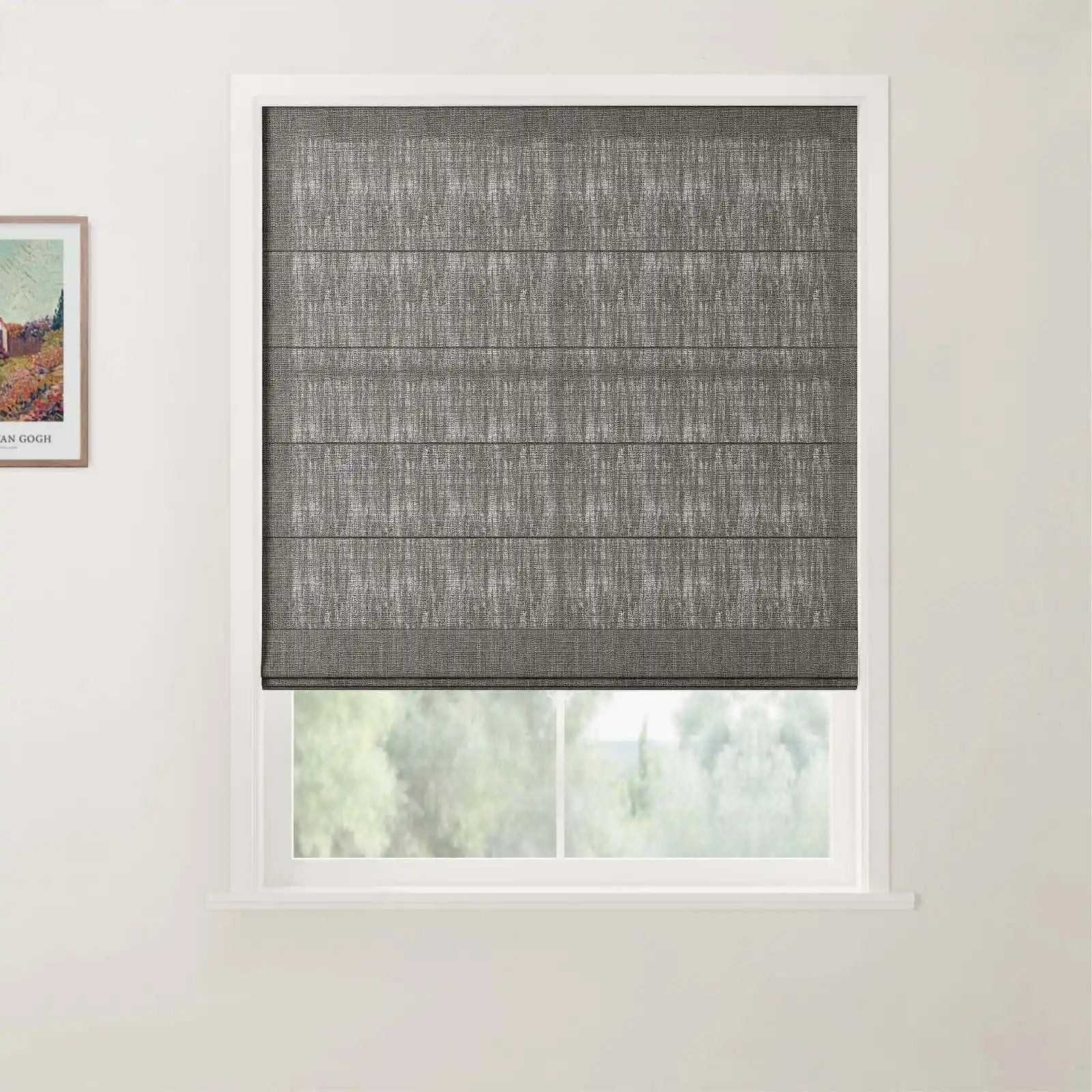 A partially visible colorful print by Van Gogh hangs on the left wall next to a dark grey textured Roman blind covering a white-framed window, offering a soft blurred view of green trees outside