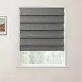 A framed print of a colorful Van Gogh landscape painting is positioned beside a window featuring a partially lowered gray textured Roman blind, with blurred green trees visible outdoors