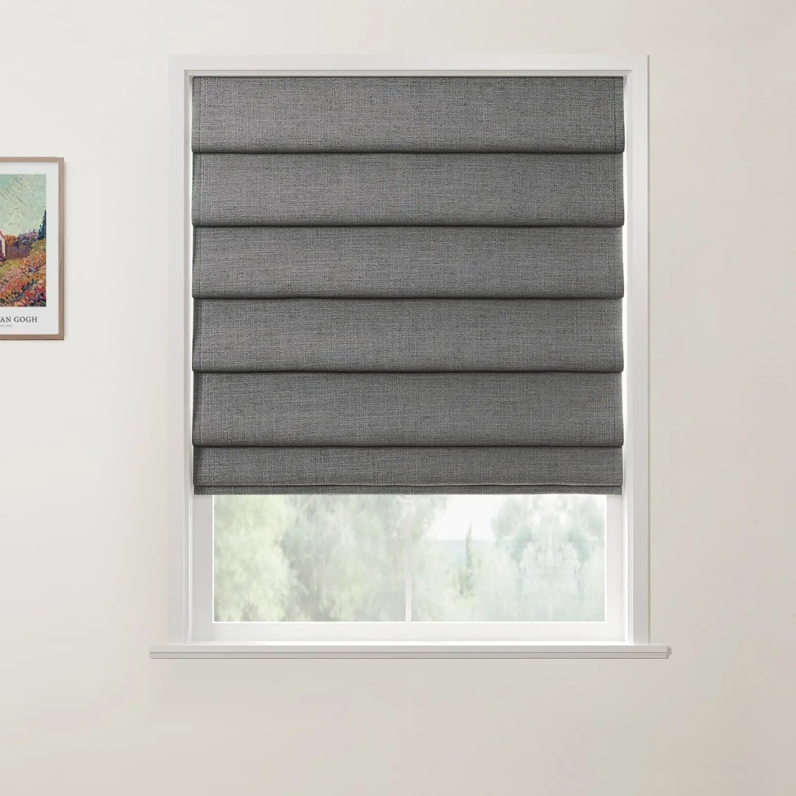 A framed print of a colorful Van Gogh landscape painting is positioned beside a window featuring a partially lowered gray textured Roman blind, with blurred green trees visible outdoors