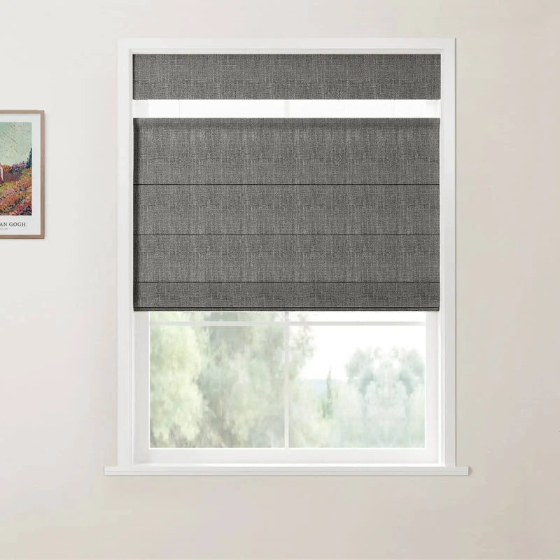 Photograph of an interior window with dark grey textured Roman blinds, a white frame, and a print of Van Gogh's The Red Vineyard on the wall showing blurred green trees outside