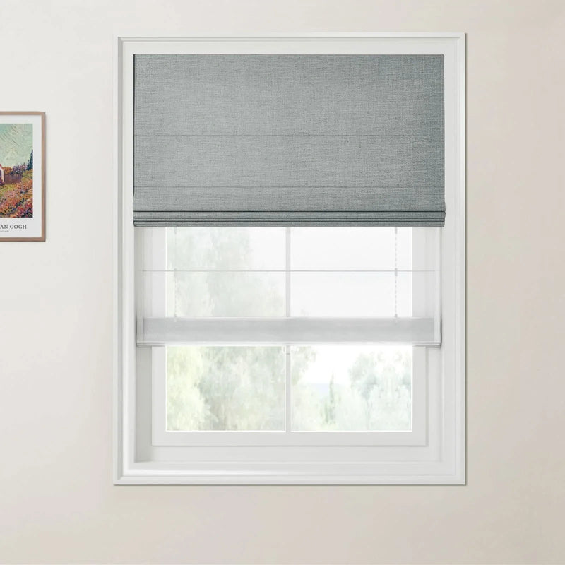 Photograph featuring a Van Gogh landscape print beside a modern interior window with a grey textured Roman shade, a sheer lower blind, and white frame looking out to blurred green trees