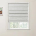 Framed print of a Van Gogh painting hanging next to a window featuring a light grey textured Roman blind in an interior room with white walls overlooking blurred green foliage