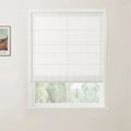 Interior photograph of a room with a window featuring a white linen-look roman blind, soft green trees visible outside, and a framed Van Gogh art print on the adjacent light wall