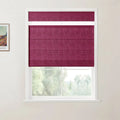 Photo of a vibrant berry-colored textured Roman blind with a top-down feature covering a white-framed window, next to a partially visible Van Gogh landscape print on a white wall, overlooking blurred green trees
