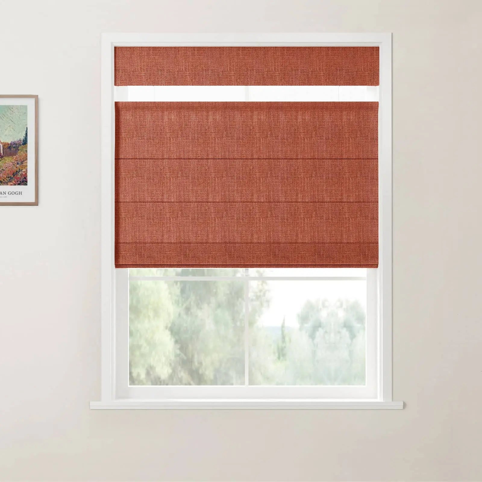 Framed Van Gogh landscape print on a white wall beside a window with a rust-red textured top-down bottom-up roman blind revealing a blurred green outdoor scene