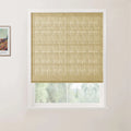 A natural tan woven Roman blind with horizontal folds covers a modern white-framed window looking out to a blurred green landscape, with a small framed Van Gogh art print on the left white wall