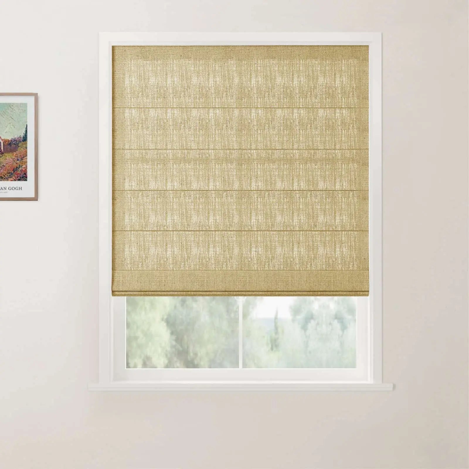 A natural tan woven Roman blind with horizontal folds covers a modern white-framed window looking out to a blurred green landscape, with a small framed Van Gogh art print on the left white wall