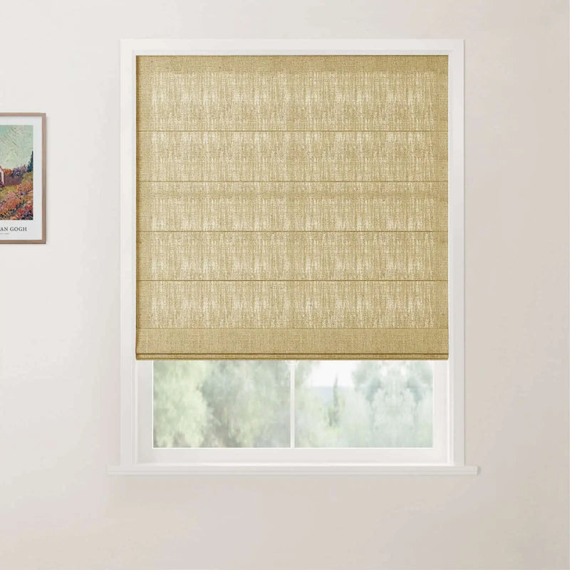 A natural tan woven Roman blind with horizontal folds covers a modern white-framed window looking out to a blurred green landscape, with a small framed Van Gogh art print on the left white wall