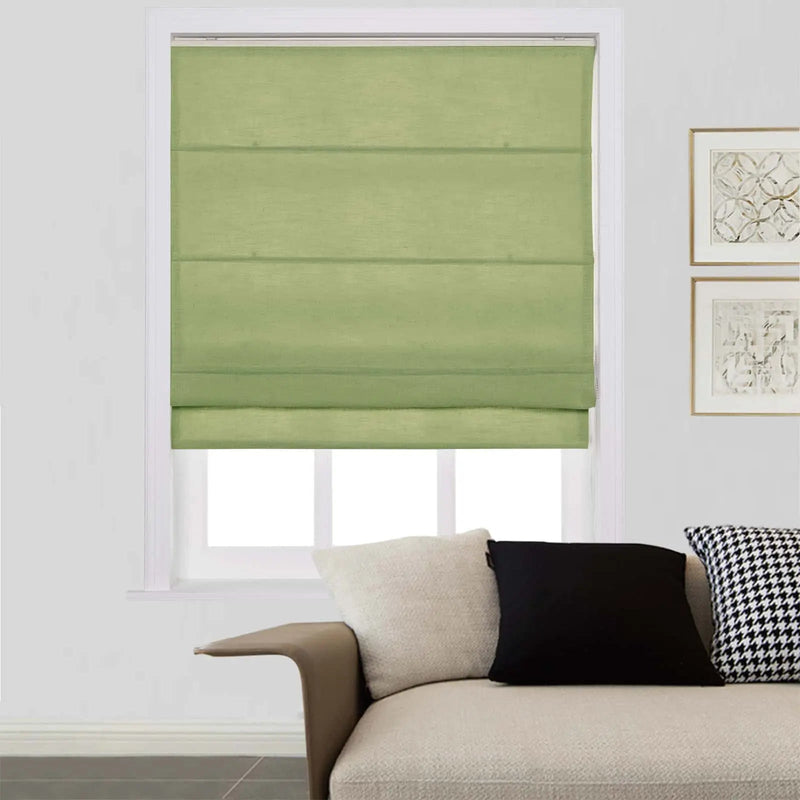 Light green Roman window shade in a modern living room featuring a neutral sofa with cream, black, and houndstooth pillows, and framed abstract art on a white wall
