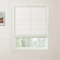 Photograph of a white framed window featuring a textured off-white Roman blind partly drawn over a view of lush green trees, with a framed Van Gogh Flowering Garden painting print on the left wall