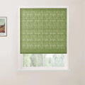 Photograph of a window in an indoor room, featuring a vibrant lime green textured Roman blind with horizontal pleats, an adjacent framed Vincent van Gogh landscape print, and a soft focus view of green trees outdoors