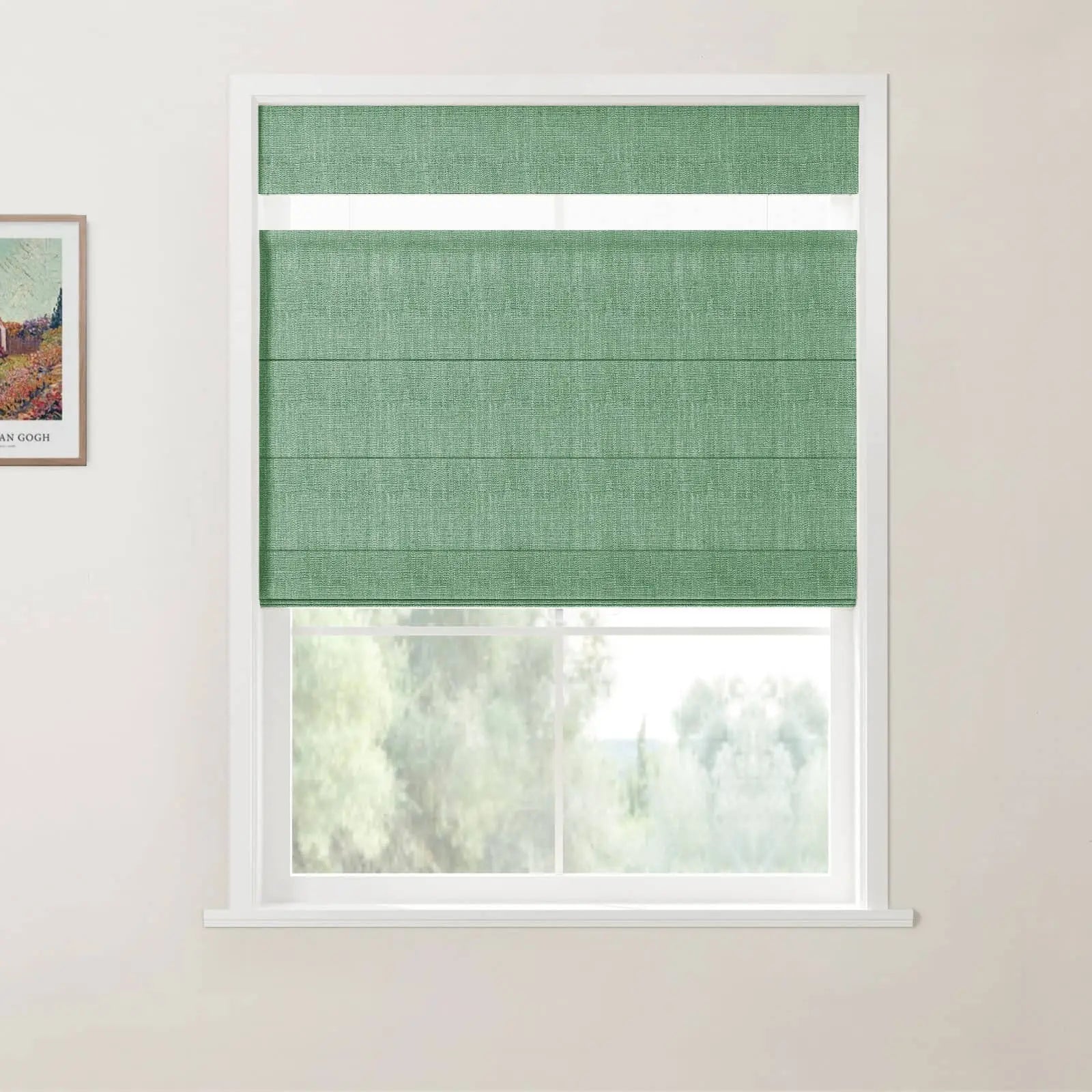 A crisp white window features a top-down, bottom-up textured green Roman blind, revealing blurred green trees outside, with a framed Van Gogh print on the adjacent white wall