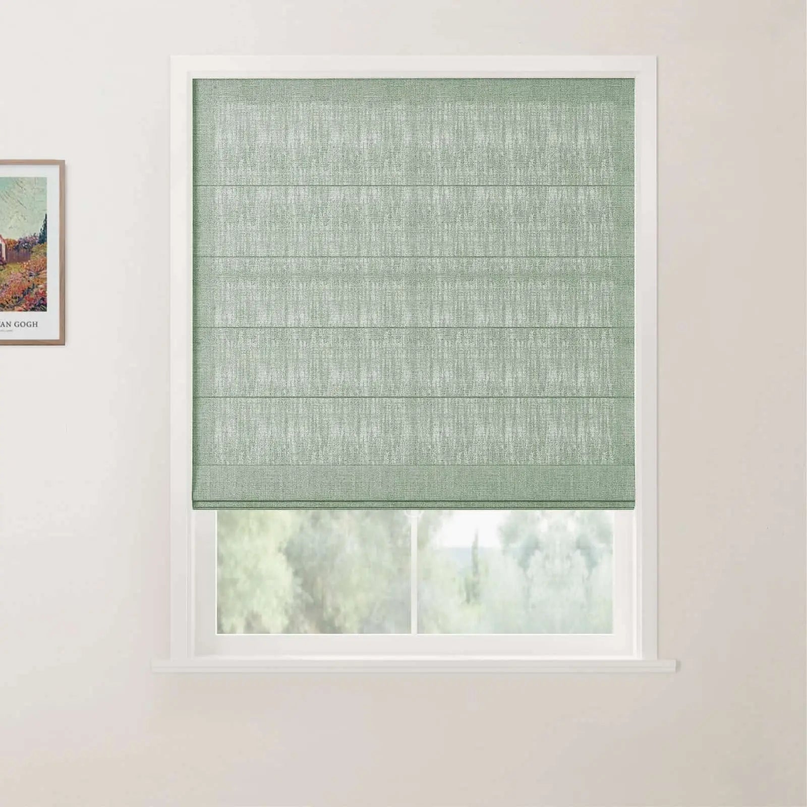 A sage green textured Roman blind with horizontal folds in a white window frame, partially revealing a blurry green landscape outside, with a framed Van Gogh print on the adjacent wall