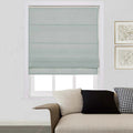 Light blue-grey Roman shade on a window in a contemporary living room with a beige sofa, black and white houndstooth pillow, and gold-framed abstract artwork