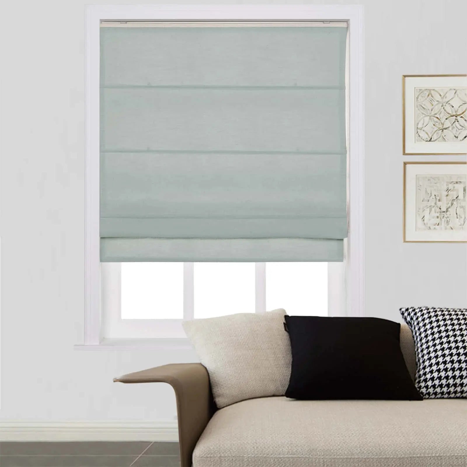 Light blue-grey Roman shade on a window in a contemporary living room with a beige sofa, black and white houndstooth pillow, and gold-framed abstract artwork