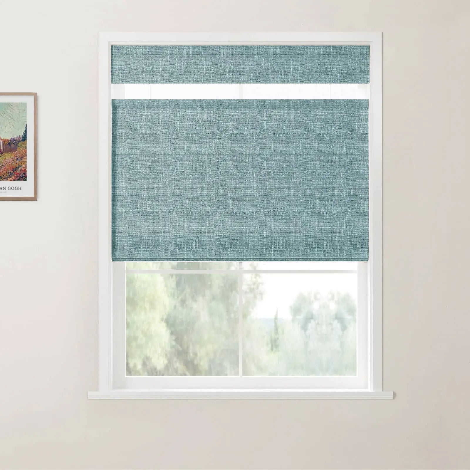 Print of Van Gogh's painting on an off-white wall next to a window featuring a partially lowered textured teal roman blind revealing blurry green trees outside