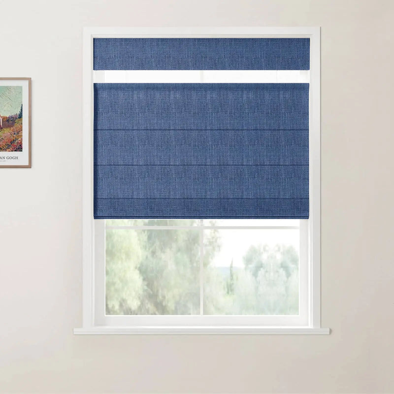 Photograph of a room featuring a white-framed window with a deep blue textured Roman blind, a framed Van Gogh landscape print on the left wall, and a blurred green outdoor view