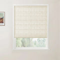 Photograph of a window in an interior room featuring a light beige linen-textured Roman blind with horizontal folds, a colorful Van Gogh landscape print on the left wall, and soft green foliage visible outside