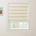 Photograph of a bright interior room featuring a cream textured Roman blind with horizontal folds partially drawn over a white window frame, offering a blurred view of green trees outside, with a framed Vincent Van Gogh Wheat Field with Cypresses poster visible on the left wall