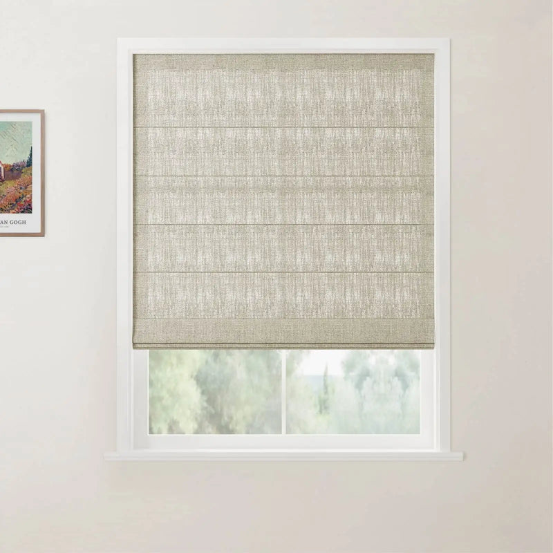 Photograph of a window featuring a textured beige Roman blind partially raised, revealing green outdoor foliage, set against a white wall with a framed Van Gogh print