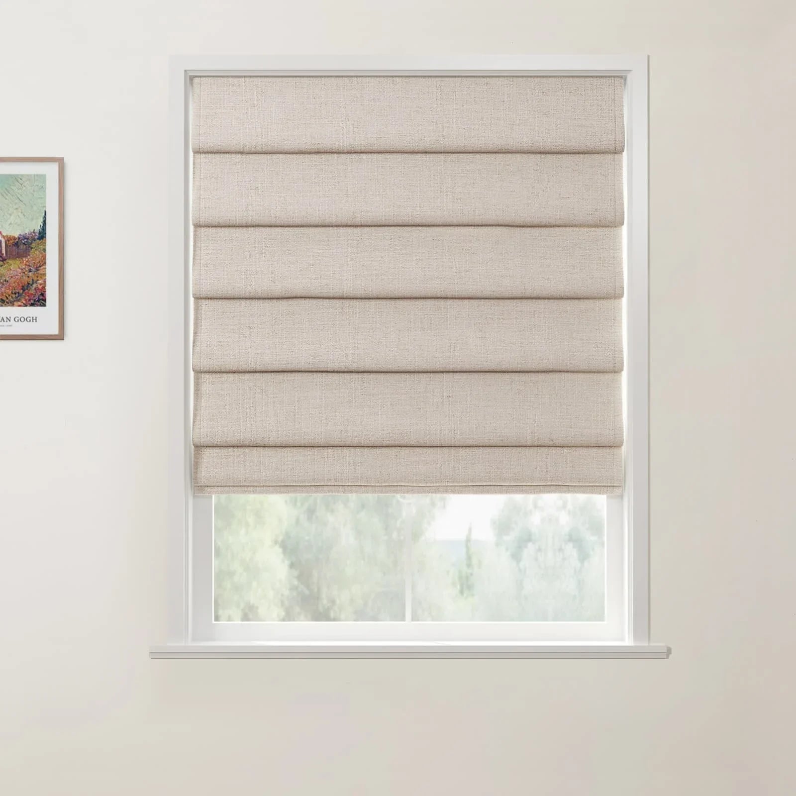 Framed print of a Van Gogh landscape painting on a white wall next to a window with a beige textured Roman shade overlooking blurred green trees