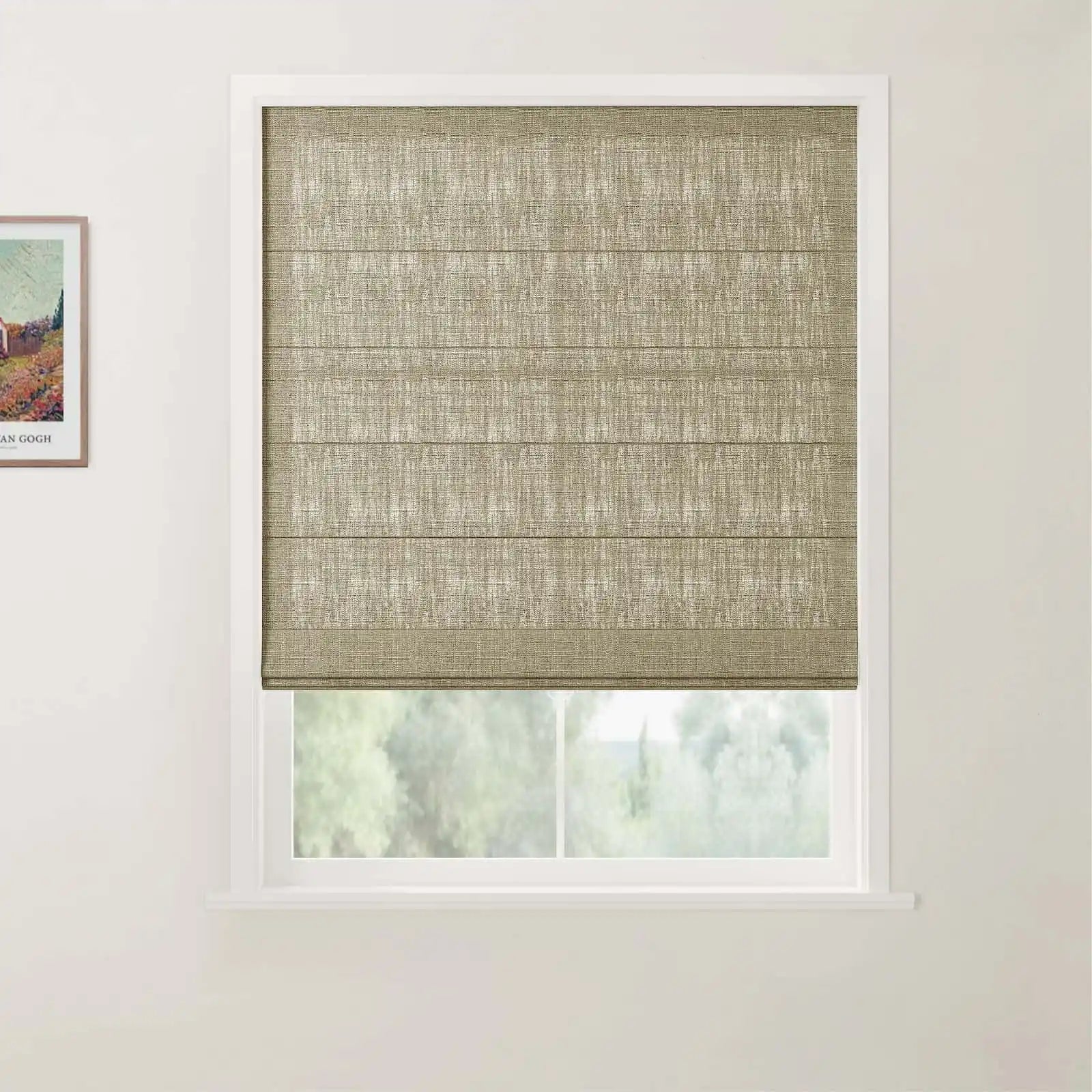 Photography of an interior room window with white trim, featuring a neatly folded fawn brown textured Roman blind, a blurred view of green trees outside, and a partially visible framed Van Gogh landscape print on the adjacent white wall