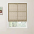 A modern room interior featuring a white-framed window with a textured beige linen Roman blind, a framed Van Gogh landscape print on the left wall, and blurred green trees visible below