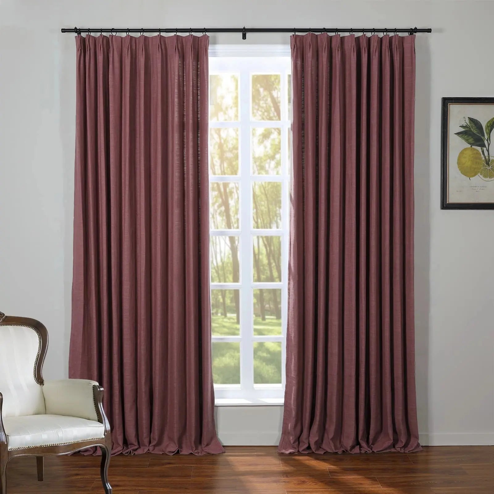 A room featuring deep rose red pinch-pleat curtains flanking a multipane window with a sunny green forest view, complemented by a white classic armchair and a framed lemon botanical print