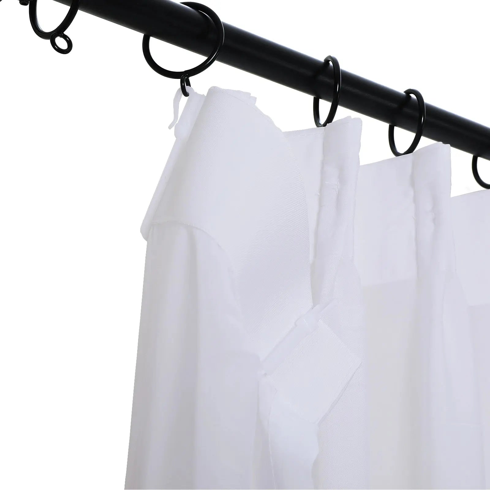 White sheer curtains with fabric tab tops suspended by black rings on a black curtain rod
