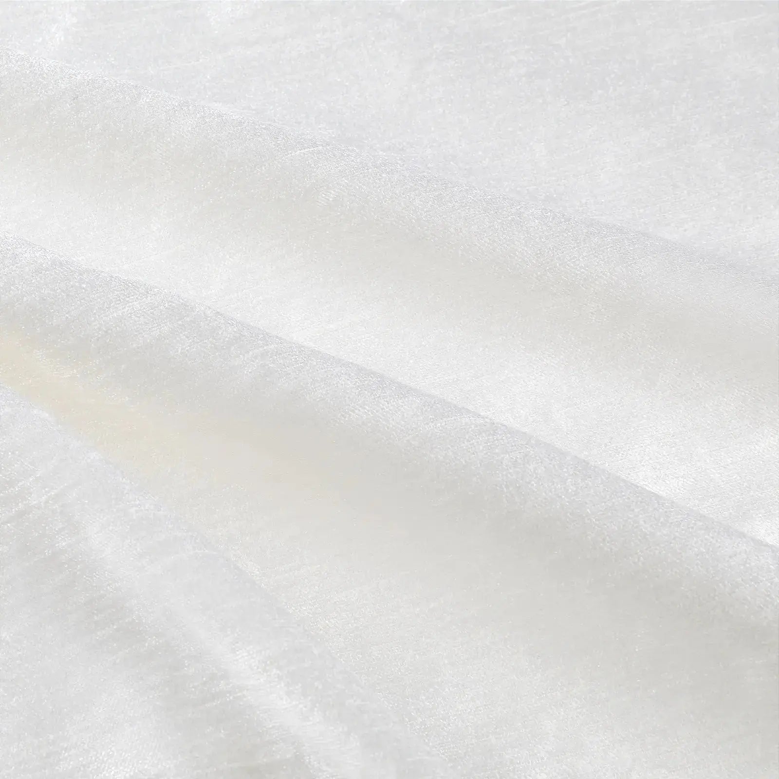 Photograph of textured white fabric displaying soft diagonal folds and subtle cream-colored shadows