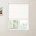 Photograph of a modern room interior featuring a white window frame with a partially lowered textured white roller shade, overlooking a lush green outdoor landscape, with a framed Van Gogh print of a vibrant field on the left wall